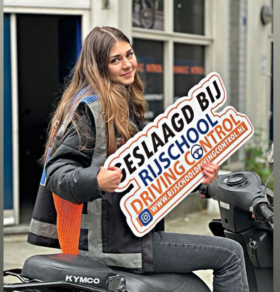 Geslaagde scooterleerling Jamal met Geslaagd-bord na scooterexamen Rotterdam bij Rijschool Driving Control